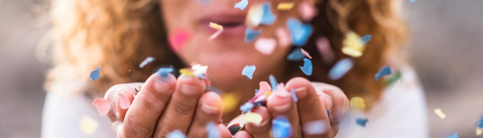 Vrouw blaast gekleurde confetti