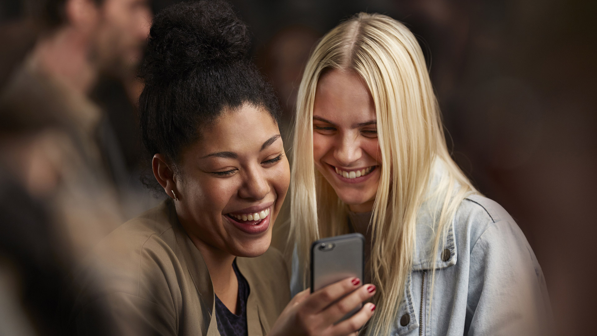 Twee vrouwen kijken lachend naar een telefoon